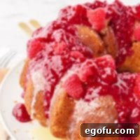Square image of White Chocolate Raspberry Cake with raspberry sauce.