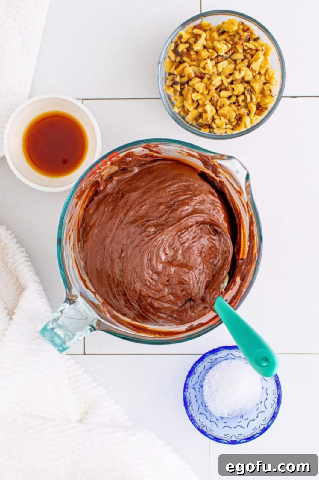 Melted chocolate chips and sweetened condensed milk being stirred together in a bowl until smooth and glossy.