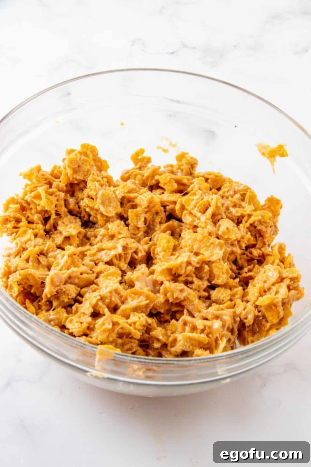 Grandmas Effortless No Bake Cornflake Delights 8 The peanut butter and corn syrup mixture being poured over the cornflakes and gently folded until every piece is fully coated.