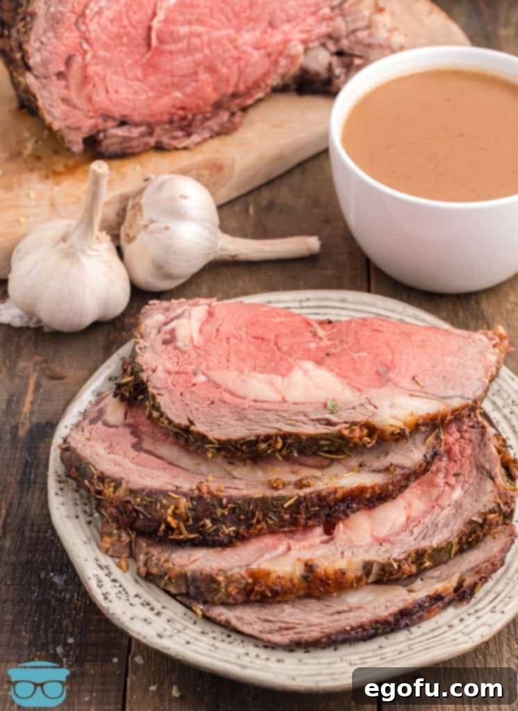 A beautifully presented slice of Garlic Butter Prime Rib on a plate, with a pool of au jus in the background, ready to be enjoyed.