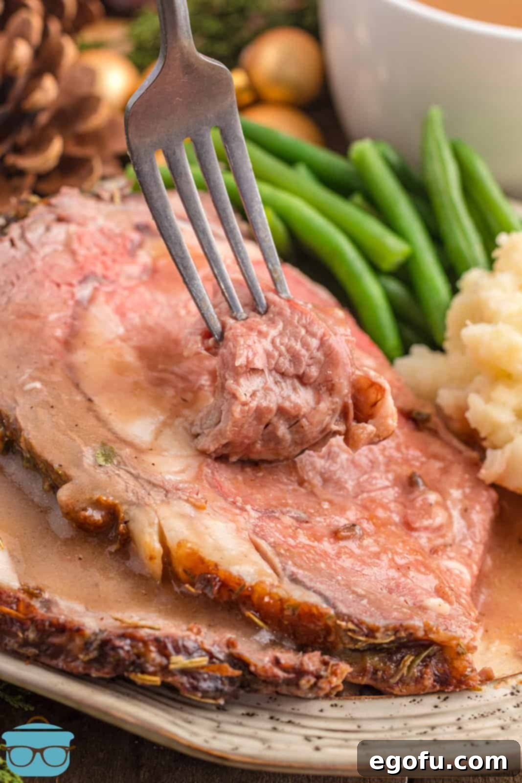 A fork taking a delicious bite out of a tender slice of Garlic Butter Prime Rib, showcasing its perfect texture and juiciness.