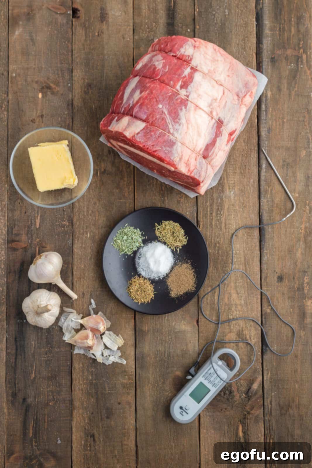 A vibrant flat lay showcasing all the fresh and dry ingredients required for the Garlic Butter Prime Rib recipe: roast, butter, garlic, herbs, salt, pepper, beef broth, flour, and Worcestershire sauce.