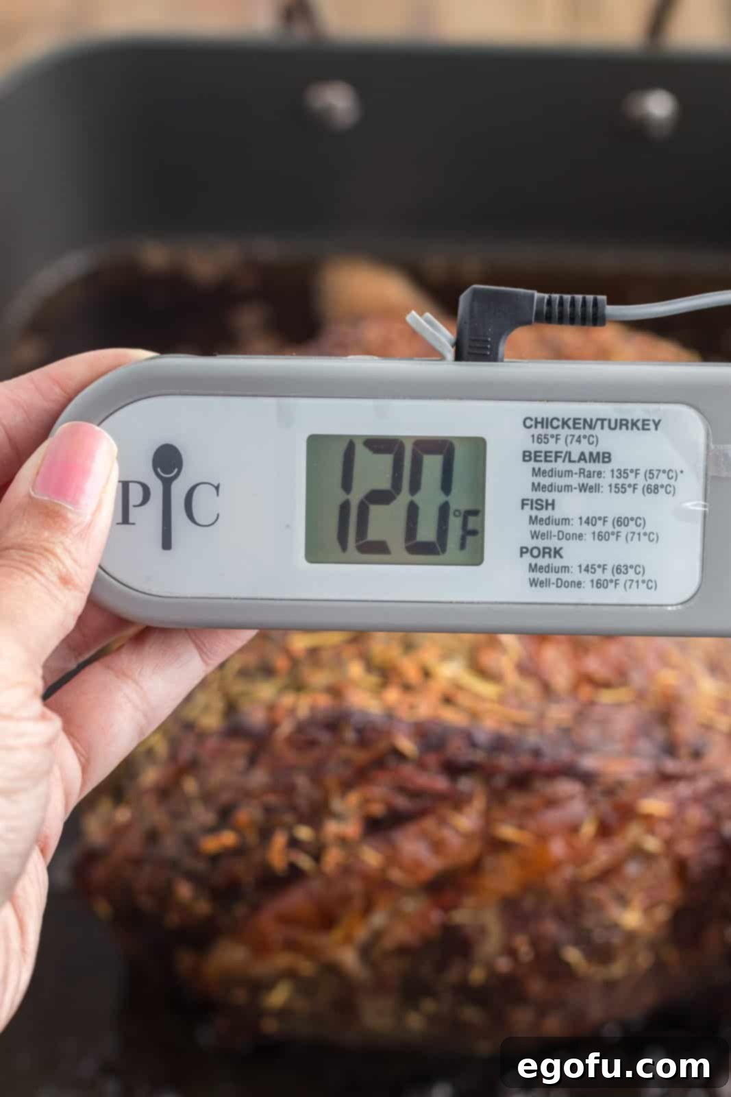 An oven-safe probe thermometer accurately inserted into the thickest part of the prime rib, displaying an internal temperature of 120 degrees Fahrenheit.