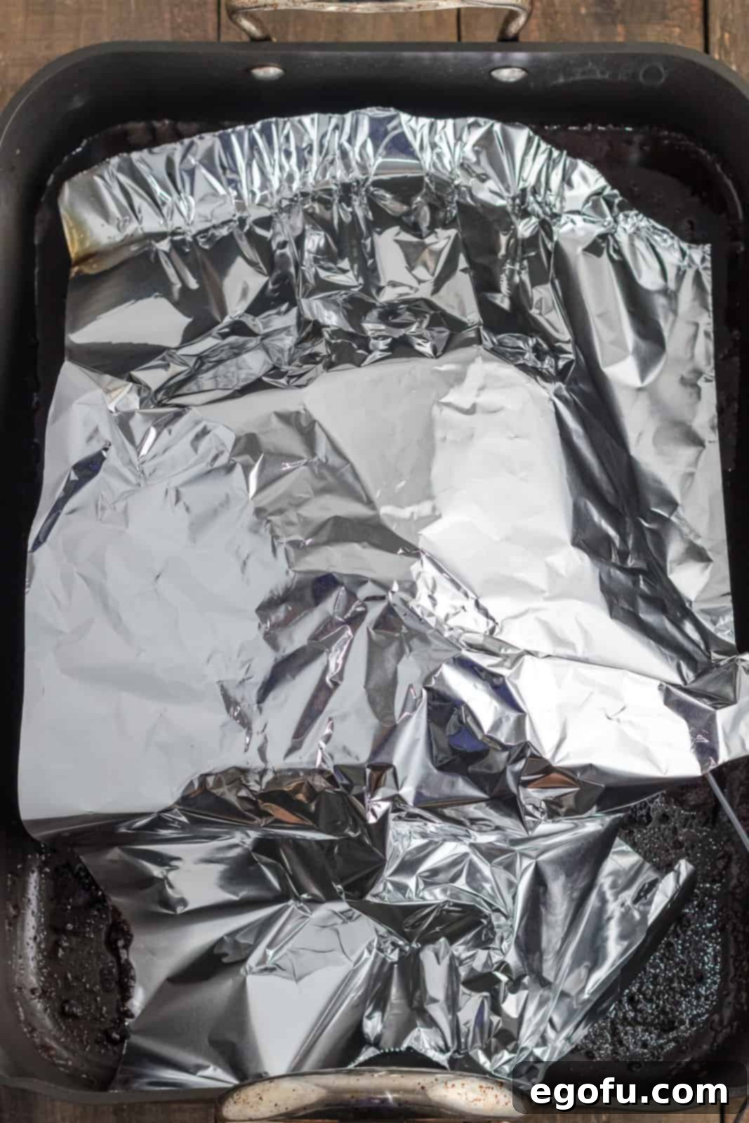 A roasted prime rib tented loosely with aluminum foil on a cutting board, undergoing the essential resting period.