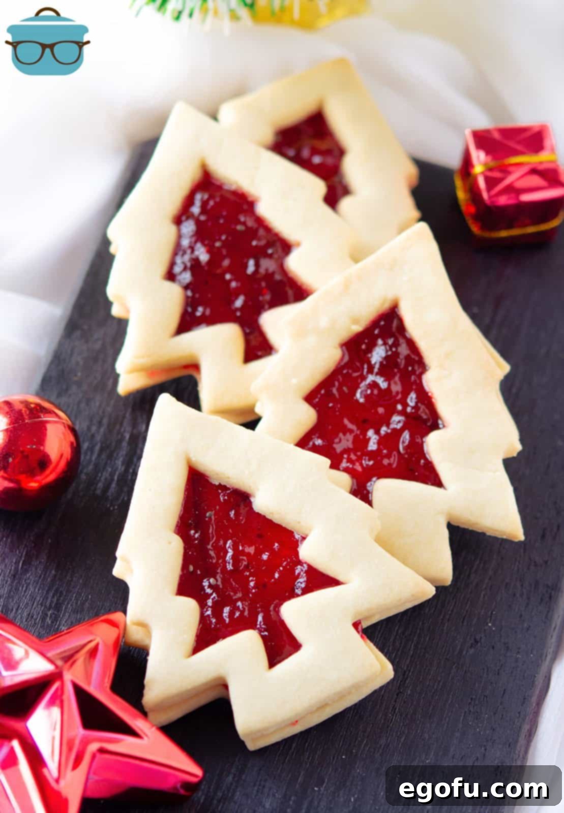 Overheard of Christmas Tree Linzeer Cookies offset layered on one another on black platter.