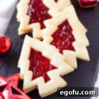 Square image of Christmas Tree Linzer cookies on black platter.