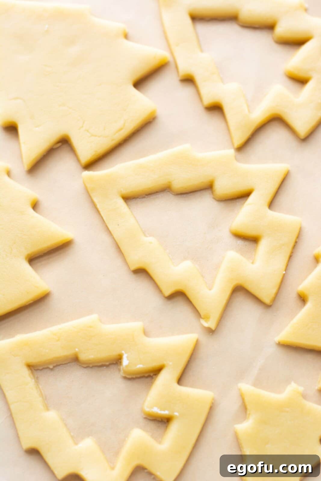 Dough cut out with cookie cutters on baking sheet.