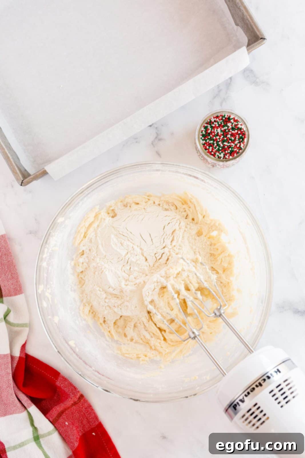 Flour being slowly added to the butter and sugar mixture in a mixer.