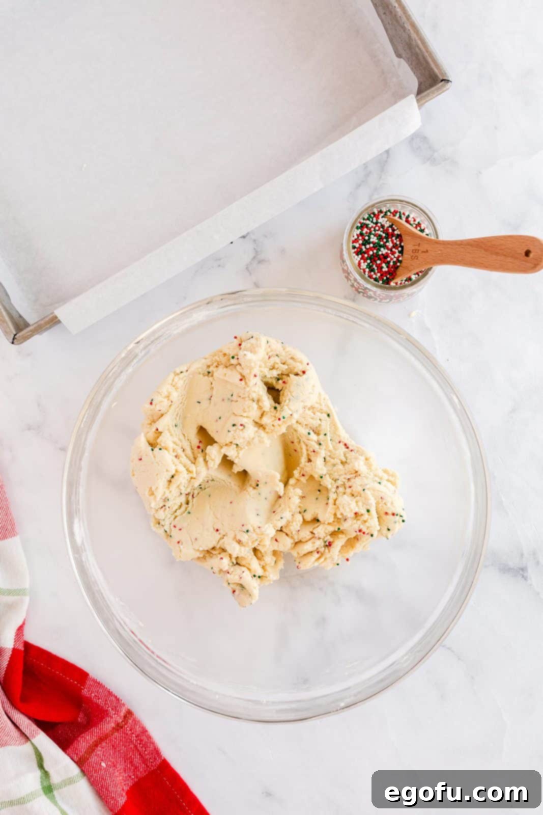 Nonpareils (sprinkles) being mixed into the shortbread cookie dough.
