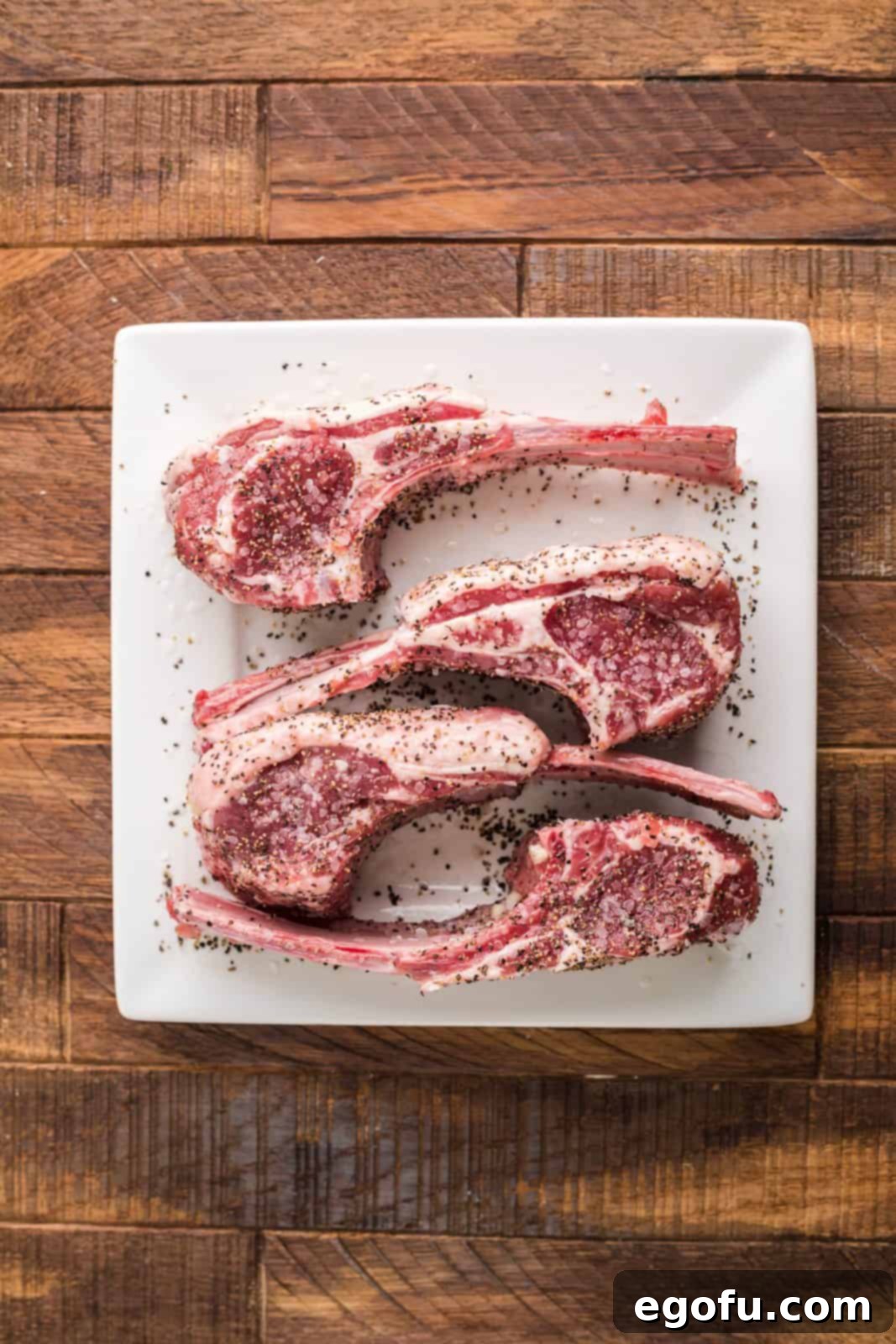Succulent Lamb Chops 7 Lamb chops, fresh from the marinade, being sprinkled with a generous amount of salt and coarse black pepper on both sides for seasoning.