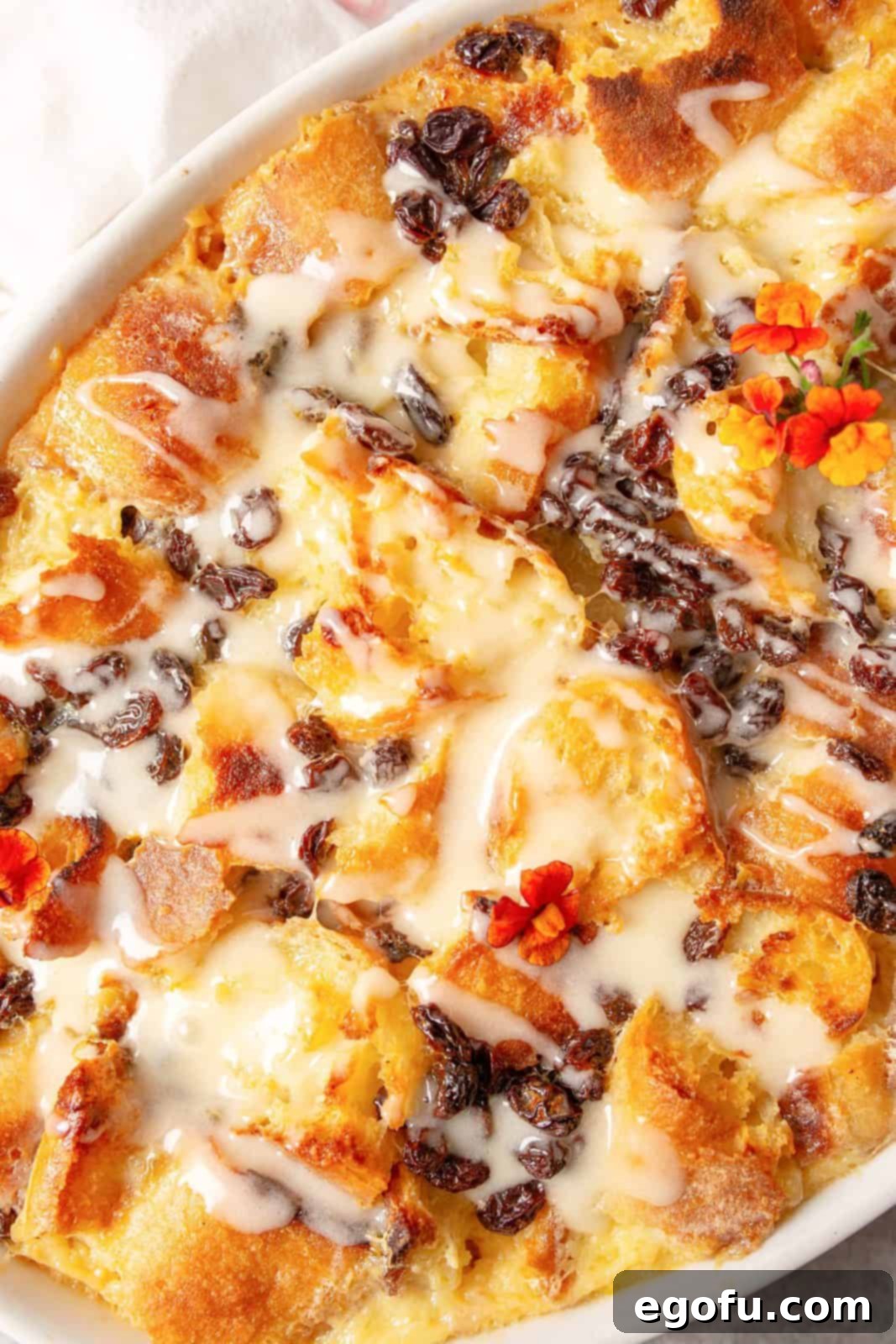 An overhead shot of the finished Old Fashioned Bread Pudding, golden and inviting, generously drizzled with a sweet, creamy sauce.