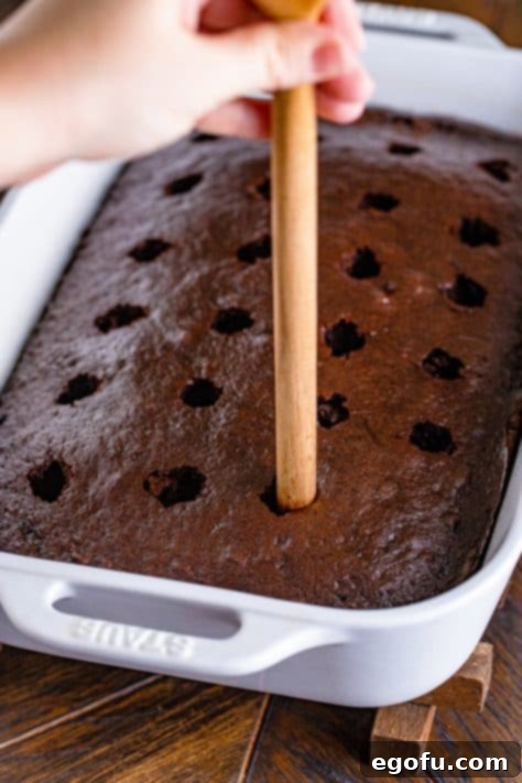 a wooden spoon handle being shown poking holes into baked cake.