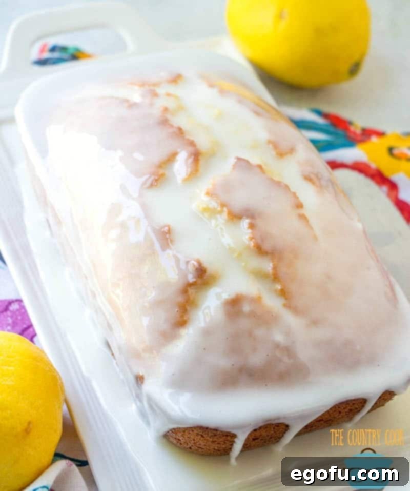 Starbucks Zesty Lemon Loaf 10 Lemon glaze being drizzled generously over a whole lemon loaf on a white platter, creating a beautiful finish.