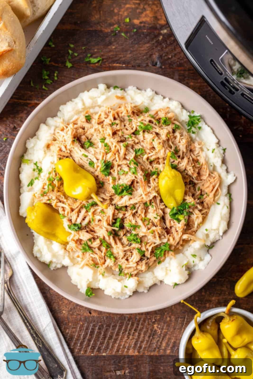 shredded crock pot chicken shown served over mashed potatoes on a plate.
