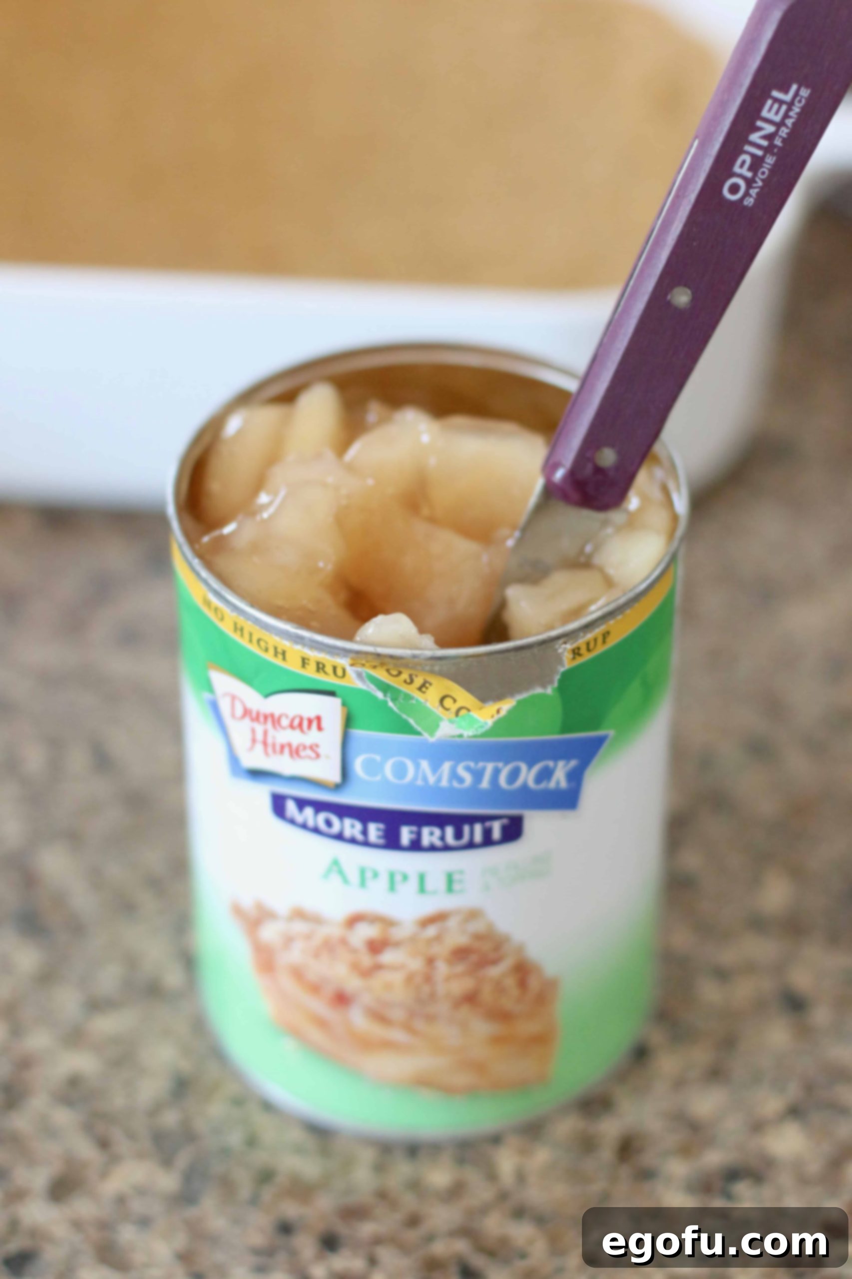 Can of apple pie filling with a knife inside cutting apples into smaller chunks.