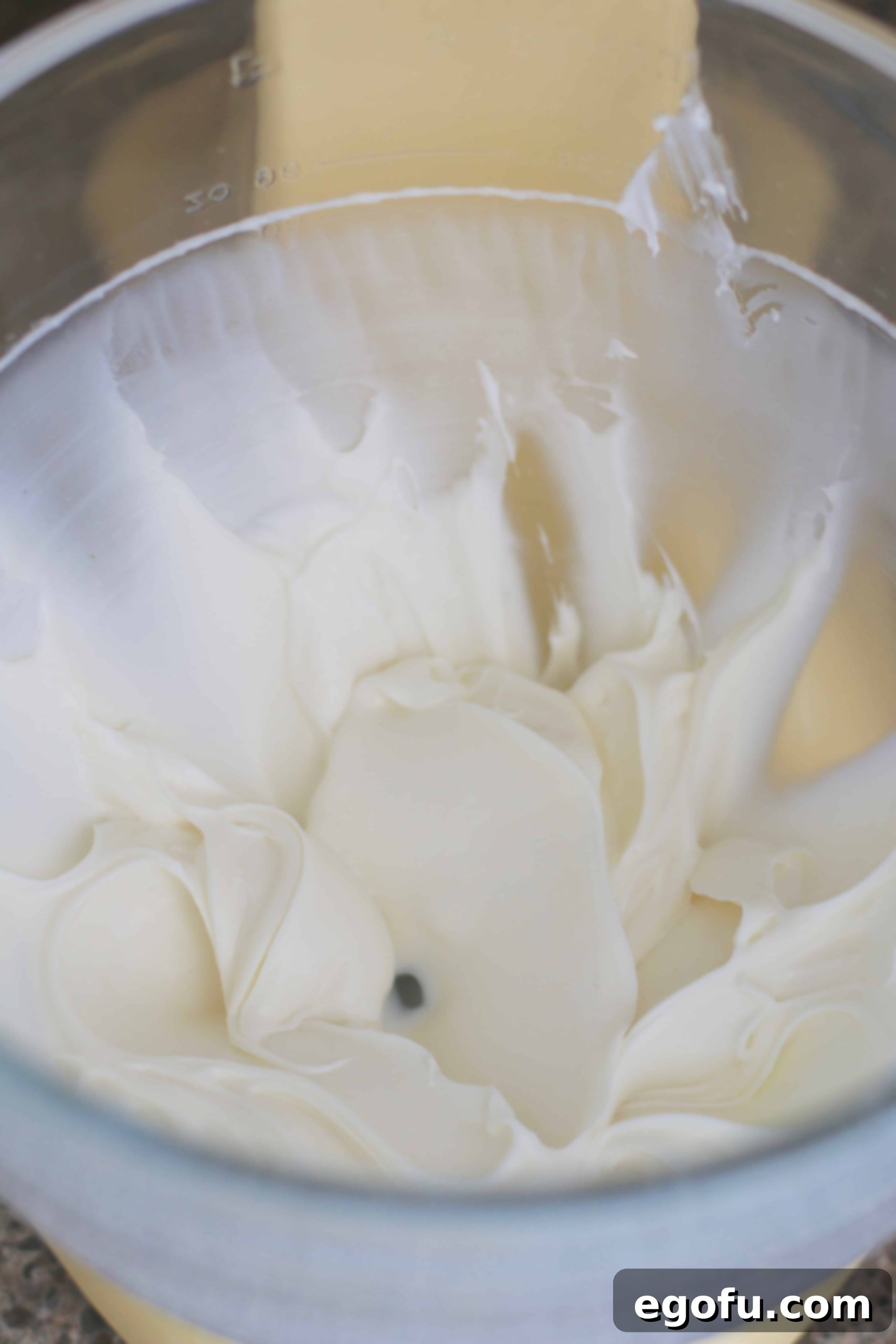 Cream cheese and sugar whipped together in a stand mixer bowl.
