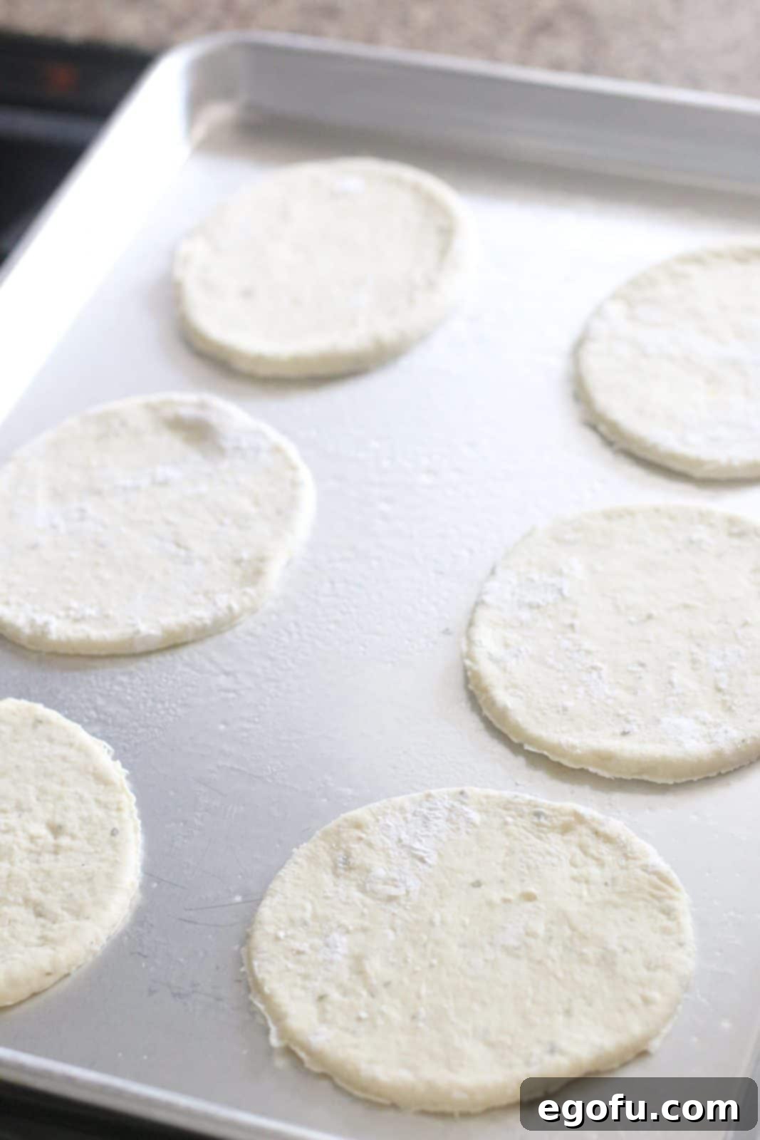Pizza dough circles neatly arranged on a silver baking sheet, ready for filling.