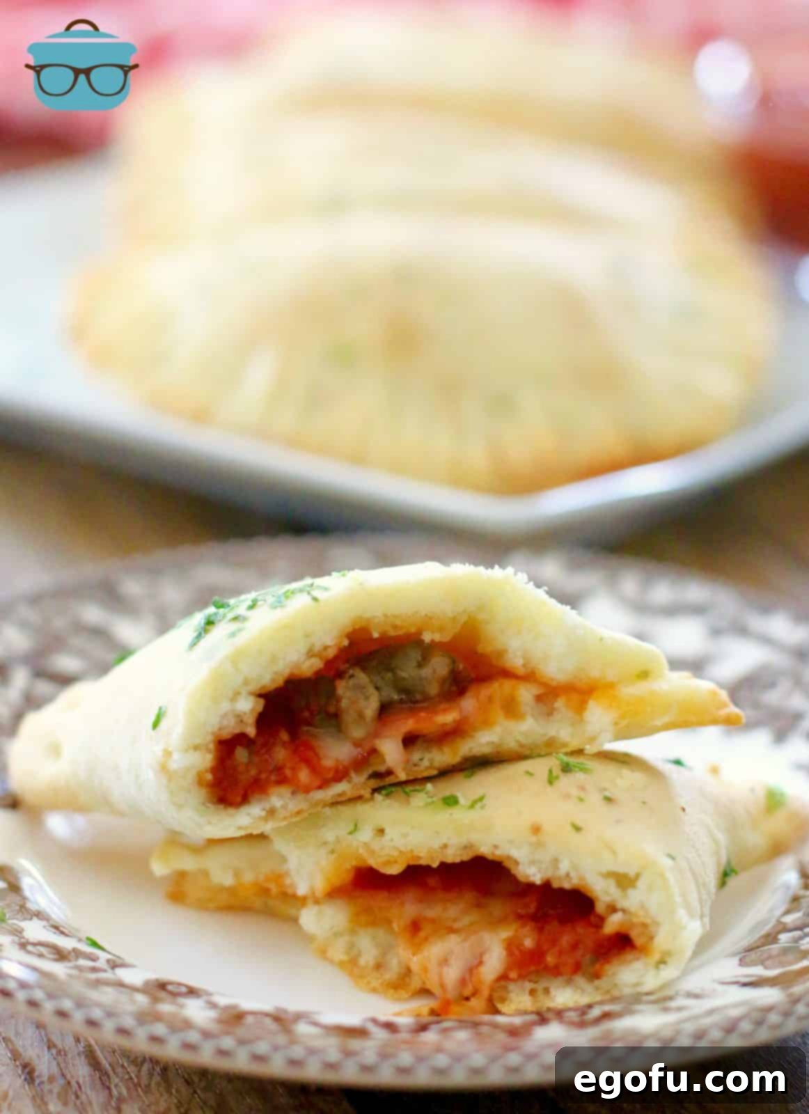 A homemade pizza pocket cut in half to showcase the warm, cheesy interior, resting on a decorative brown Spode plate.