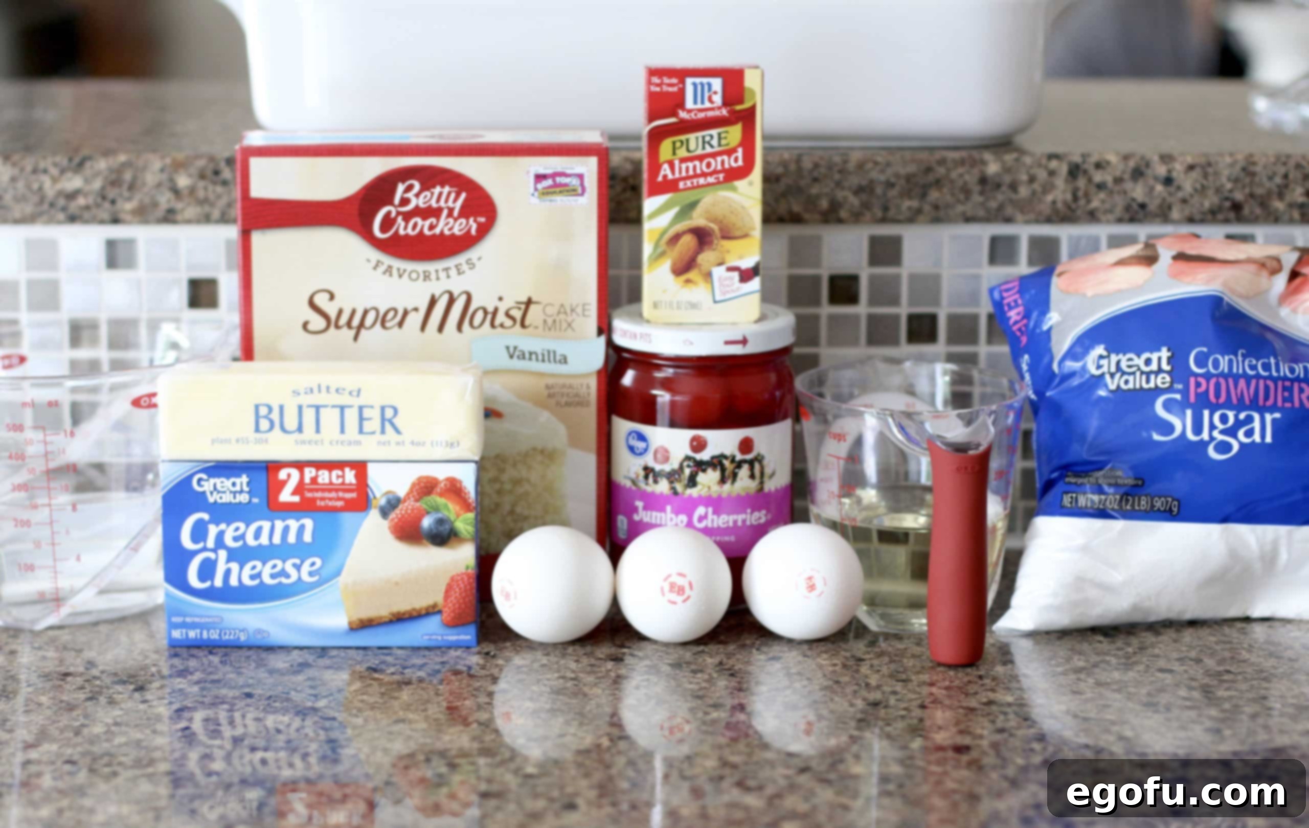 A collage of essential ingredients for Maraschino Cherry Cake: vanilla boxed cake mix, a jar of maraschino cherries, almond extract, cream cheese, butter, eggs, vegetable oil, and powdered sugar, all neatly arranged.