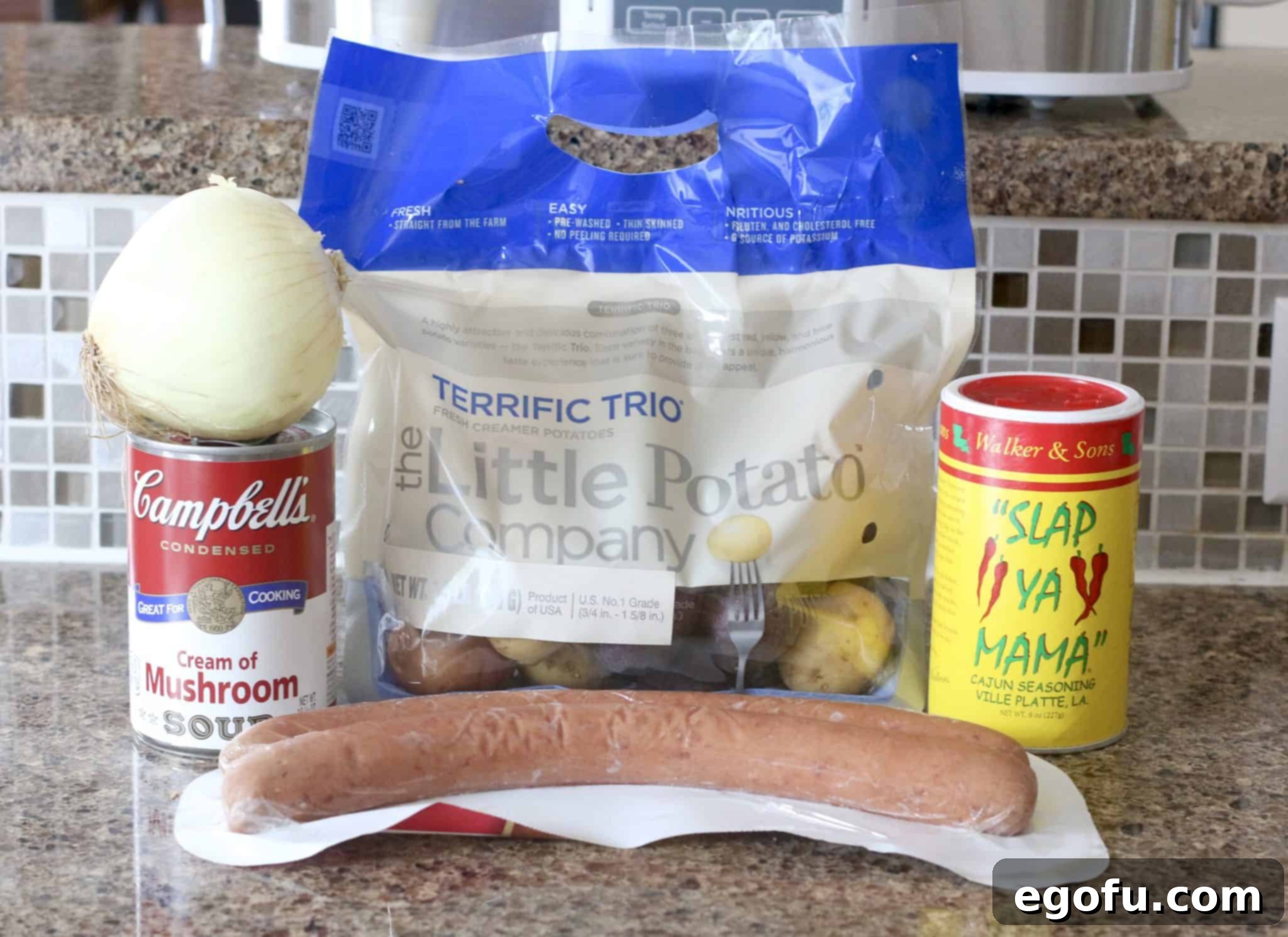 Easy Slow Cooker Creamy Sausage and Potatoes 3 A selection of raw ingredients for creamy sausage and potatoes: baby potatoes, a can of cream of mushroom soup, kielbasa sausage, a chopped onion, and Cajun seasoning.