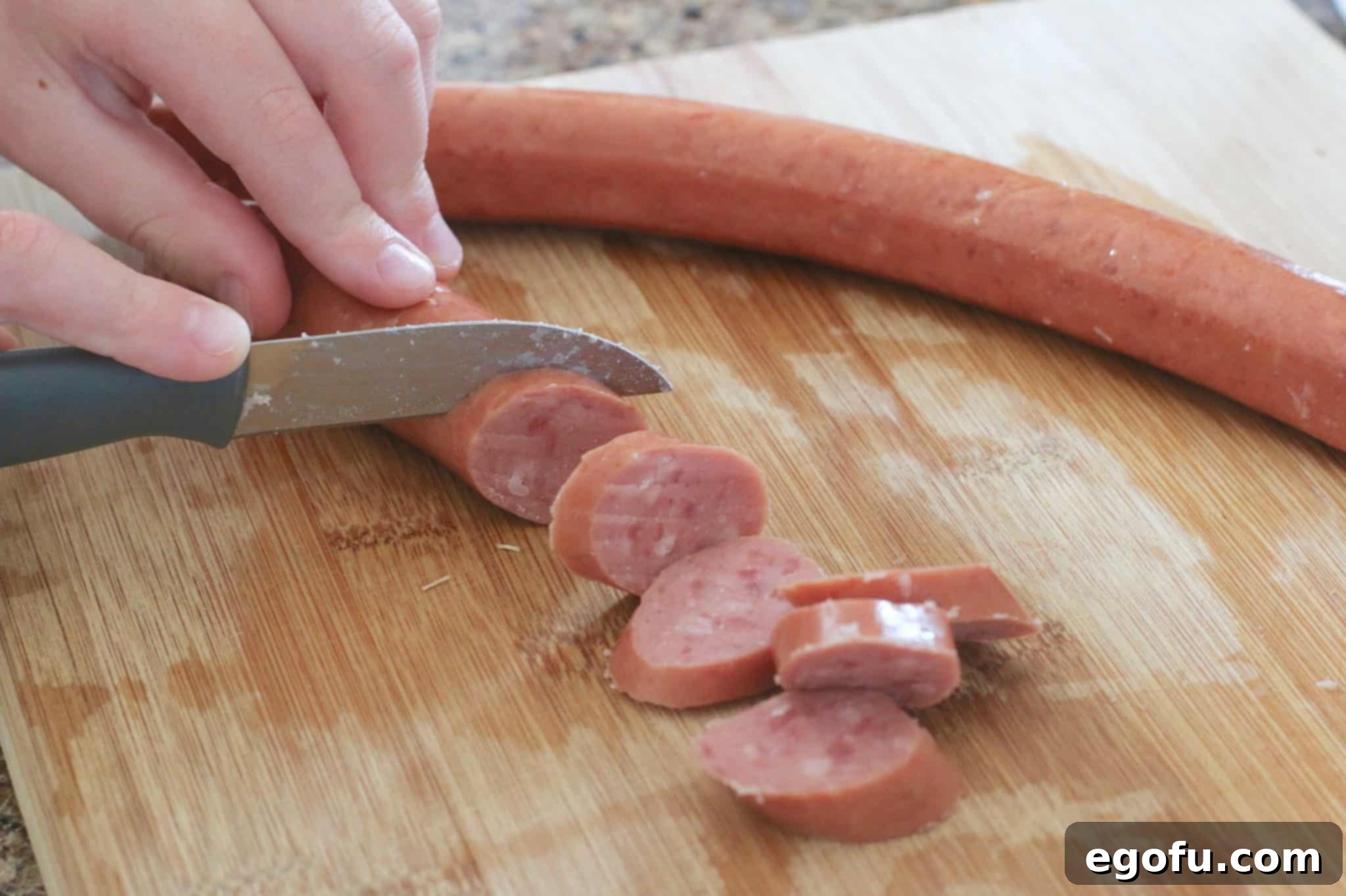 Easy Slow Cooker Creamy Sausage and Potatoes 5 Sliced smoked sausage pieces placed into a slow cooker over a layer of potatoes.