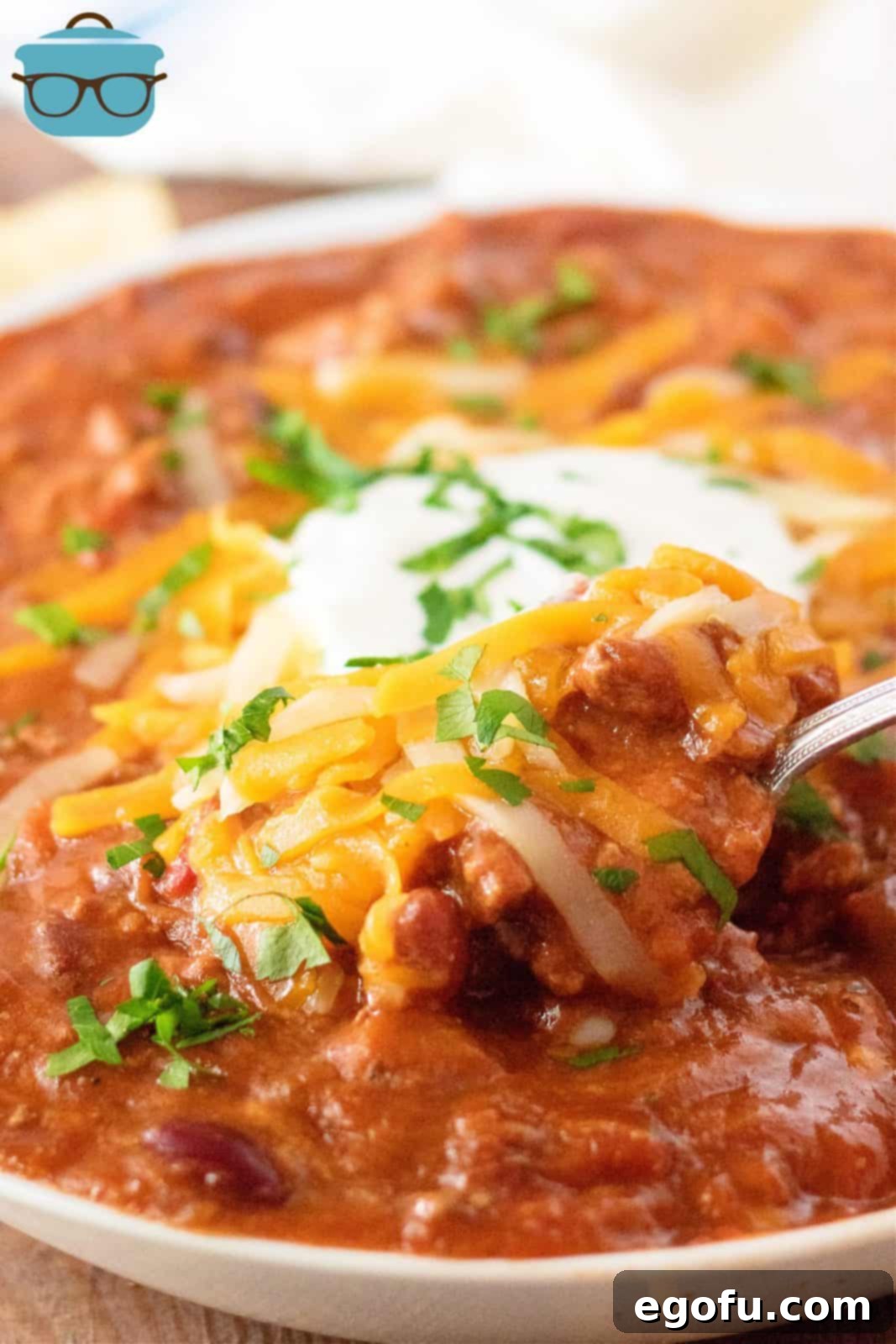 A spoon scooping thick, hearty Slow Cooker Ultimate Beef Chili from a bowl, highlighting its rich texture and ingredients.