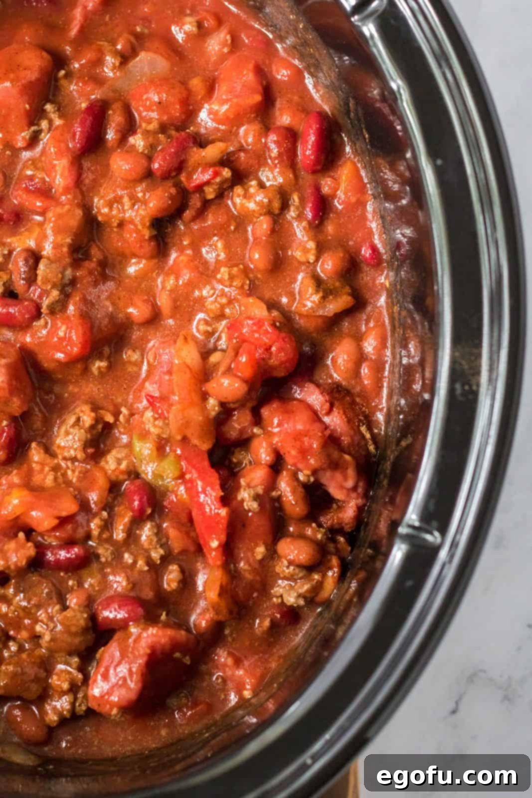 Ingredients for Slow Cooker Ultimate Beef Chili are thoroughly stirred together in the slow cooker, ensuring even distribution of flavors.