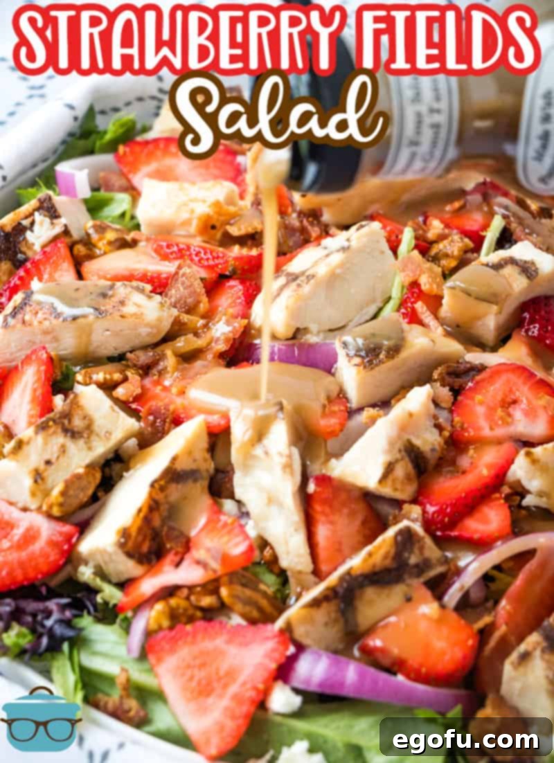 Balsamic dressing being poured over the fresh Strawberry Fields Salad with grilled chicken and feta.