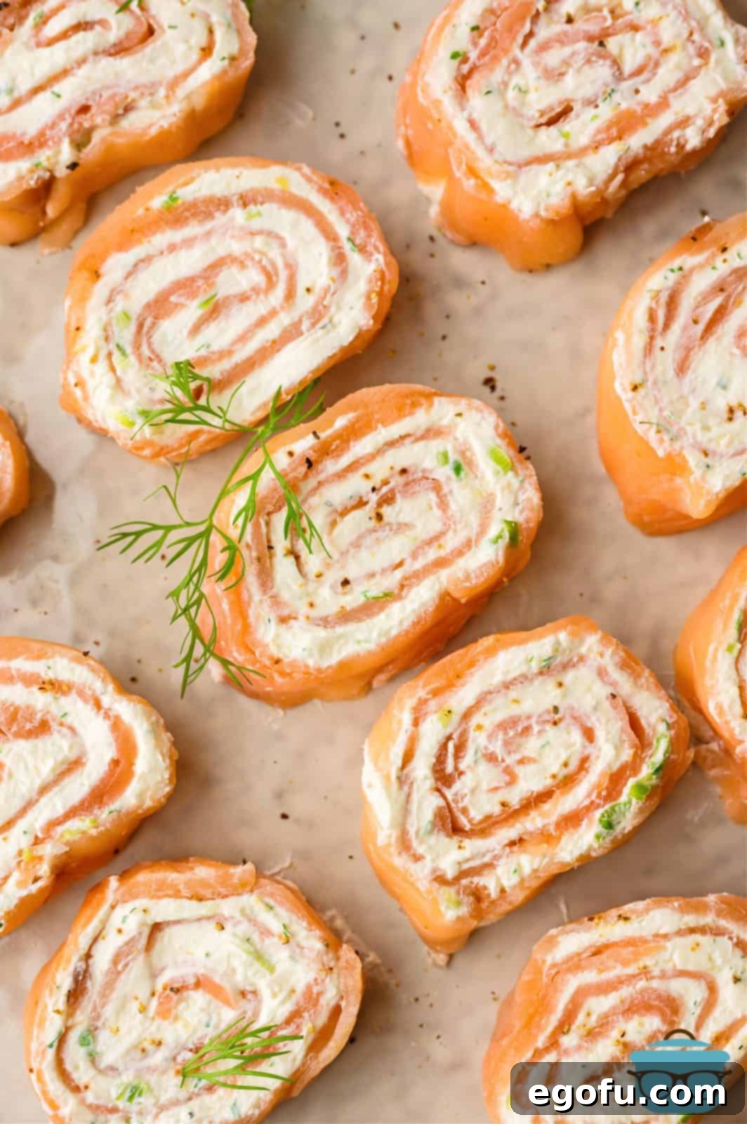 Overhead view of perfectly sliced Salmon Pinwheels arranged on rustic brown parchment paper, ready to serve.