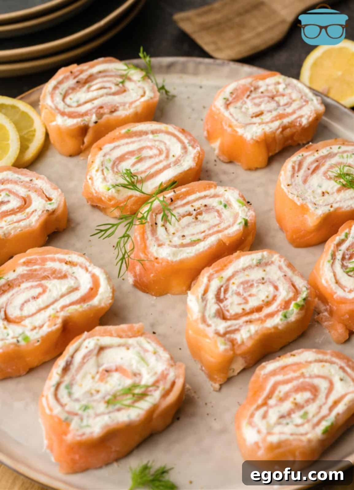 An inviting angle shot of freshly sliced Salmon Pinwheels garnished with fresh dill, presented beautifully on a serving platter.