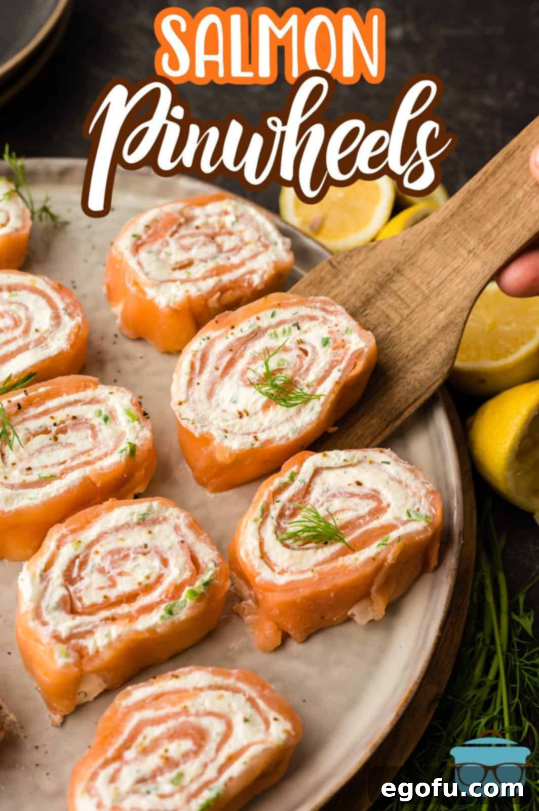 Beautiful Pinterest-style image of perfectly rolled and sliced Salmon Pinwheels, with one piece delicately placed on a wooden spatula.