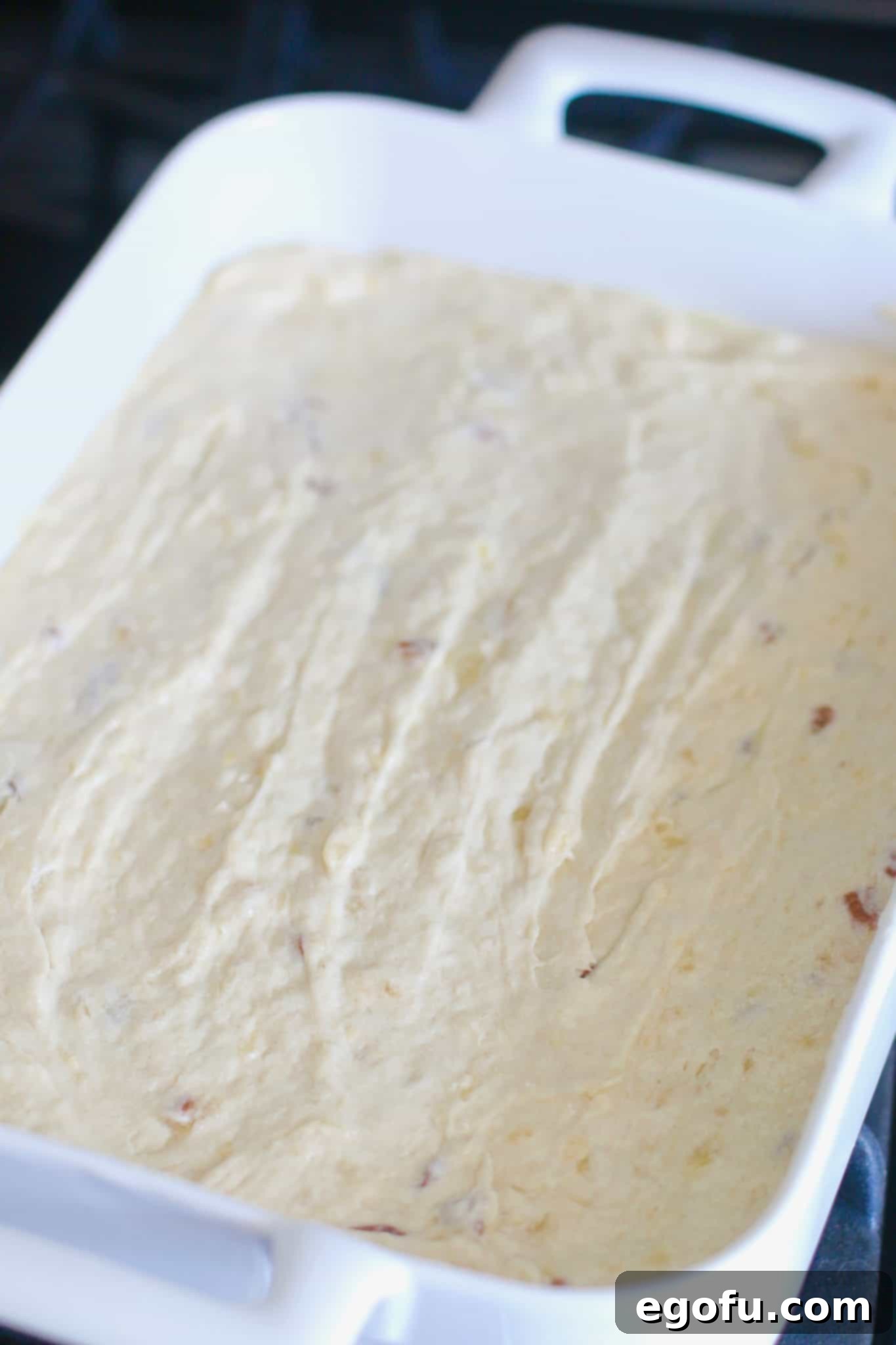 The smooth hummingbird cake bars batter spread evenly into a white Revol 9x13 baking dish, ready to be baked.