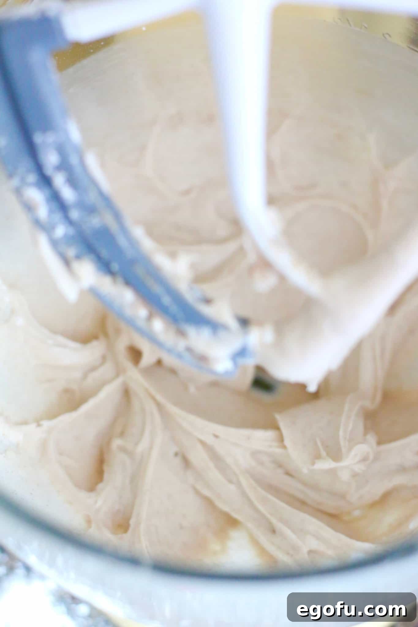 Close-up view of the perfectly smooth and creamy Cinnamon Cream Cheese Frosting in a mixing bowl, ready to be spread.