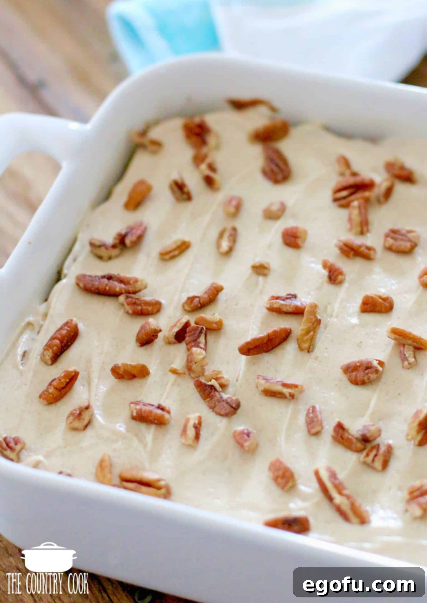 Frosted Hummingbird Cake Bars generously topped with a sprinkle of chopped pecans, ready to be cut and served.