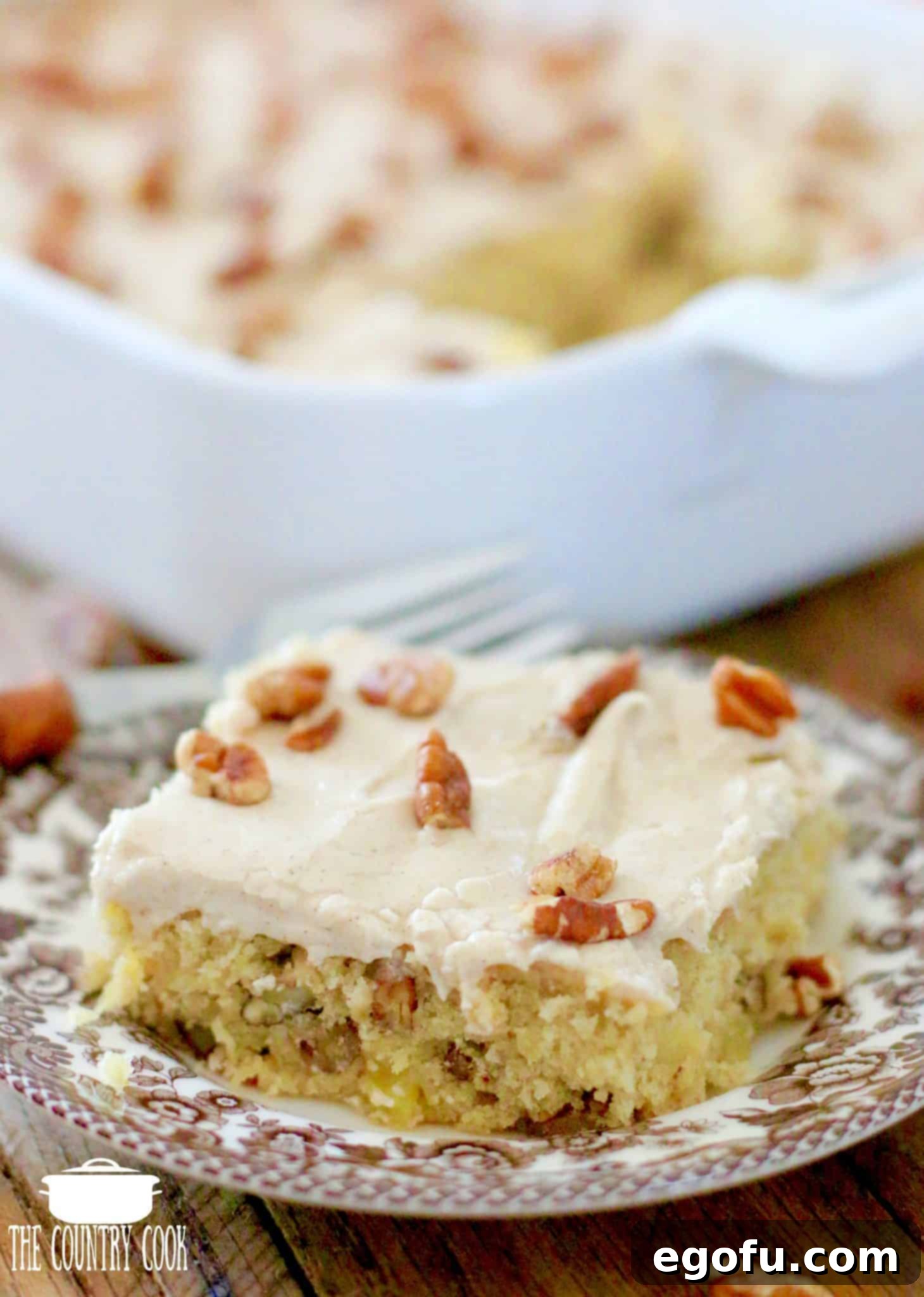 A perfectly portioned Hummingbird Cake Bar served elegantly on a patterned Spode Delamere plate with a wooden-handled fork.