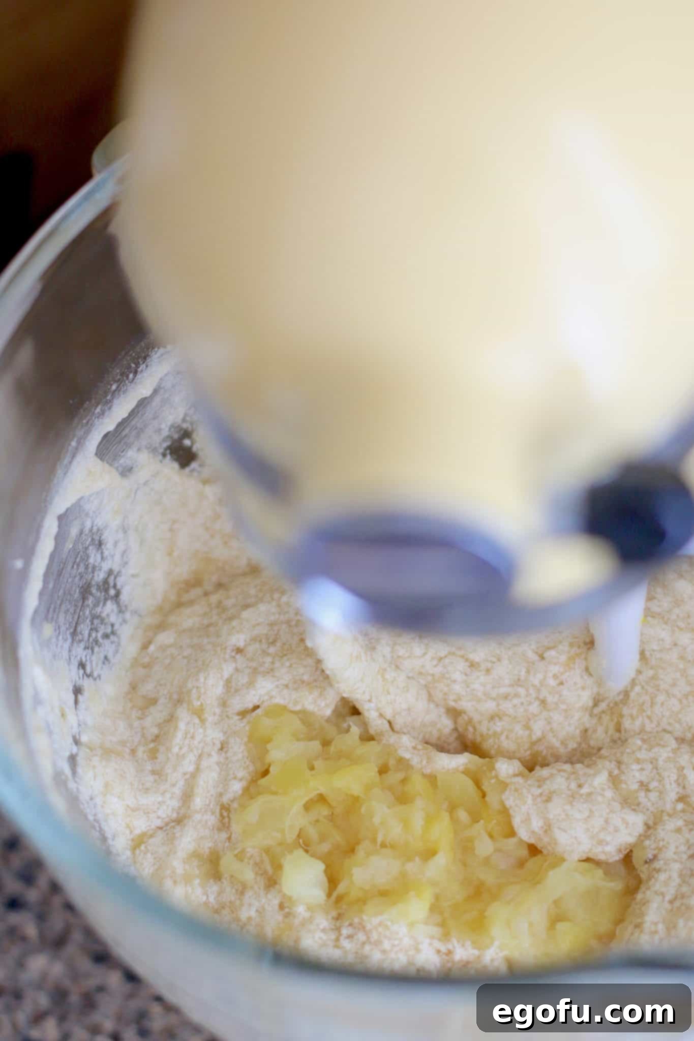 Crushed pineapple and mashed ripe bananas being added to the creamy hummingbird cake batter in a stand mixer.