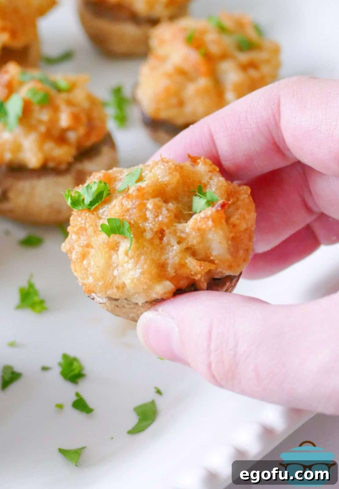 Savory Crab-Filled Mushroom Bites 9 Hand holding up one Crab Cake Stuffed Mushroom.