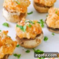 Savory Crab-Filled Mushroom Bites 10 Square image of Crab Cake Stuffed Mushrooms topped with parsley on white plate.