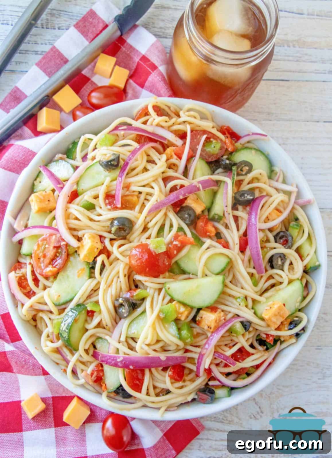 An overhead shot of a delightful spaghetti and vegetable salad, beautifully arranged in a large white serving bowl, ready for a summer meal.