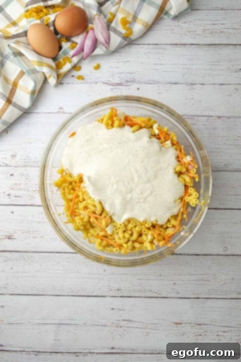 Creamy Hawaiian Macaroni Salad 13 dressing mixture added to macaroni noodles in a large glass bowl.
