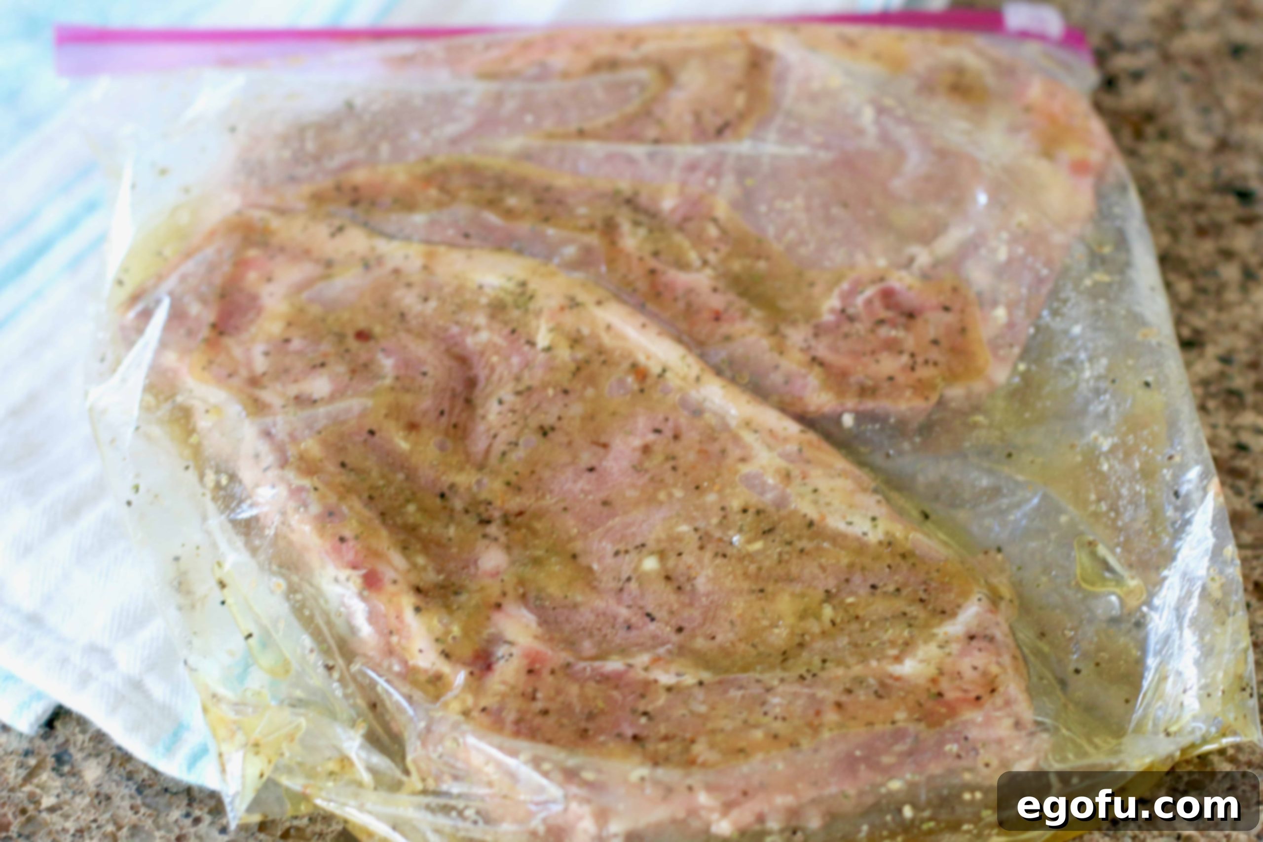 Two ribeye steaks are submerged in steakhouse marinade within a sealed plastic bag, ready for refrigeration.