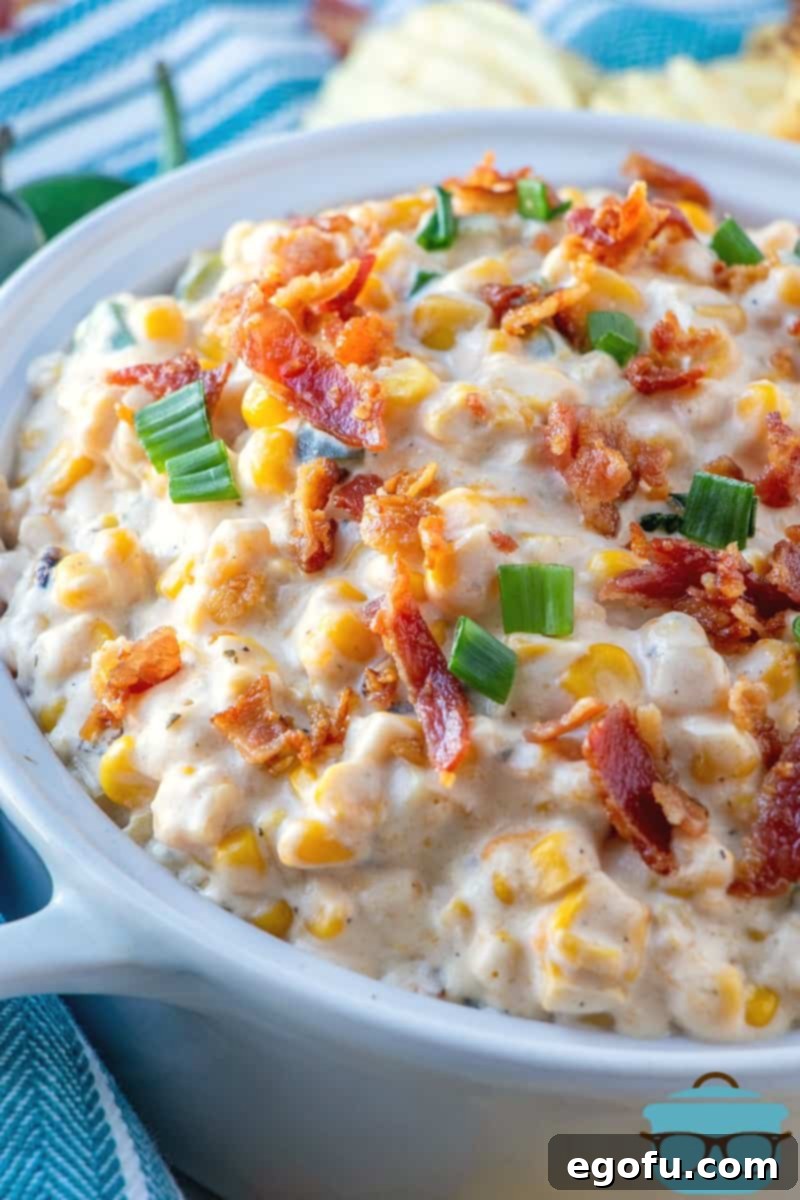 Creamy Jalapeno Corn Dip topped with sliced green onion and crispy bacon bits, served in a white bowl.