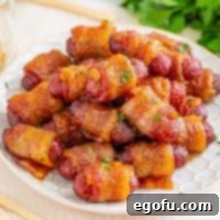 Crispy Bacon Sausage Bites 11 Square image of Brown Sugar Bacon Wrapped Little Smokies close up on white plate topped with parsley.