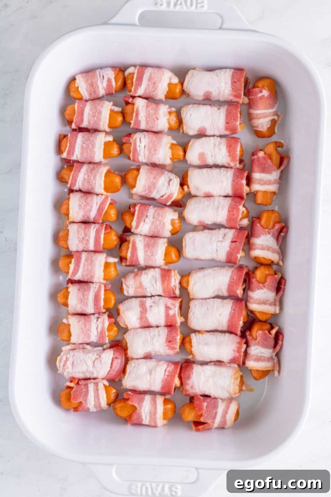 Crispy Bacon Sausage Bites 5 Little Smokies wrapped in bacon in baking dish.