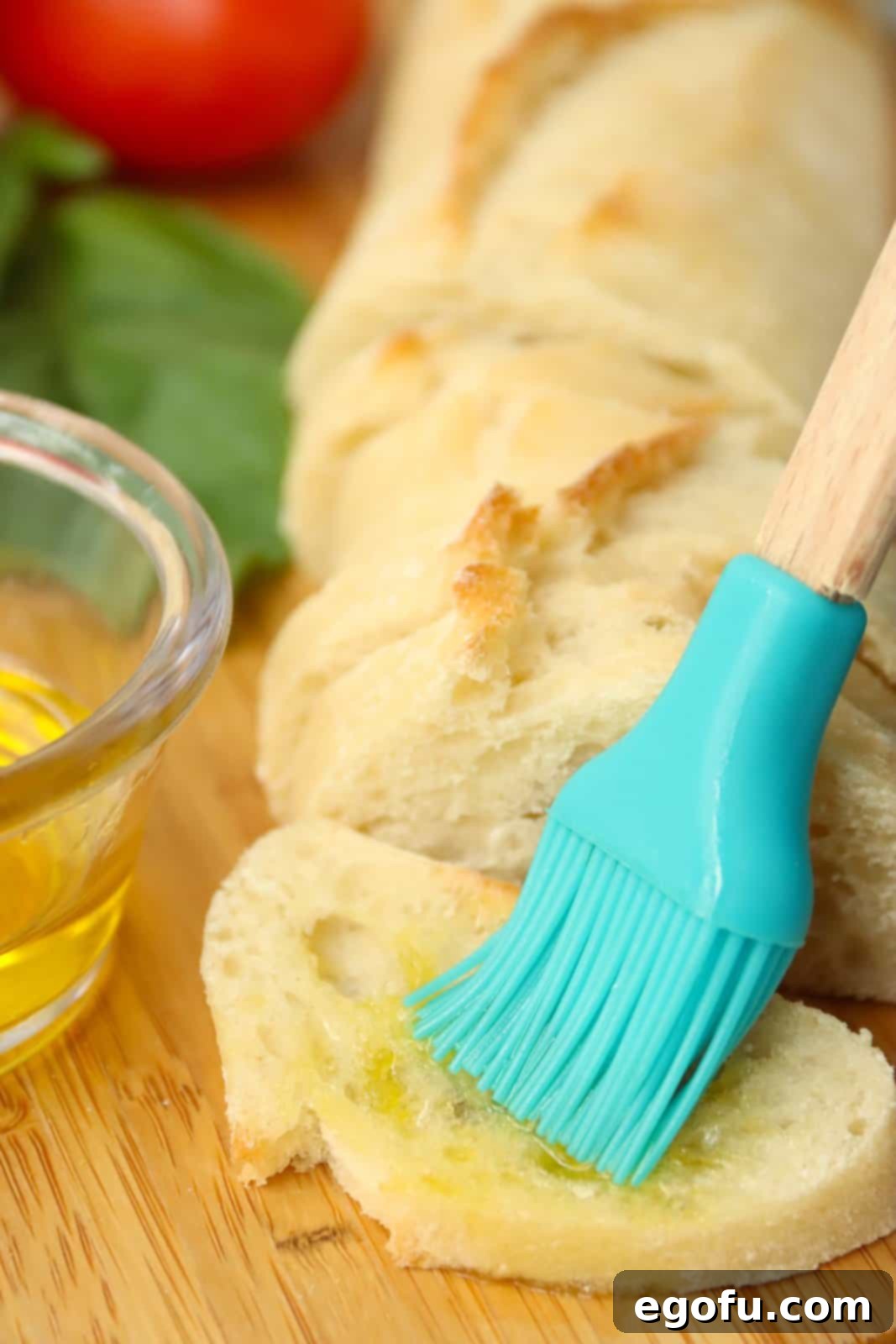 Garlic Parmesan Crostini 5 Pastry brush brushing oil on a baguette slice.