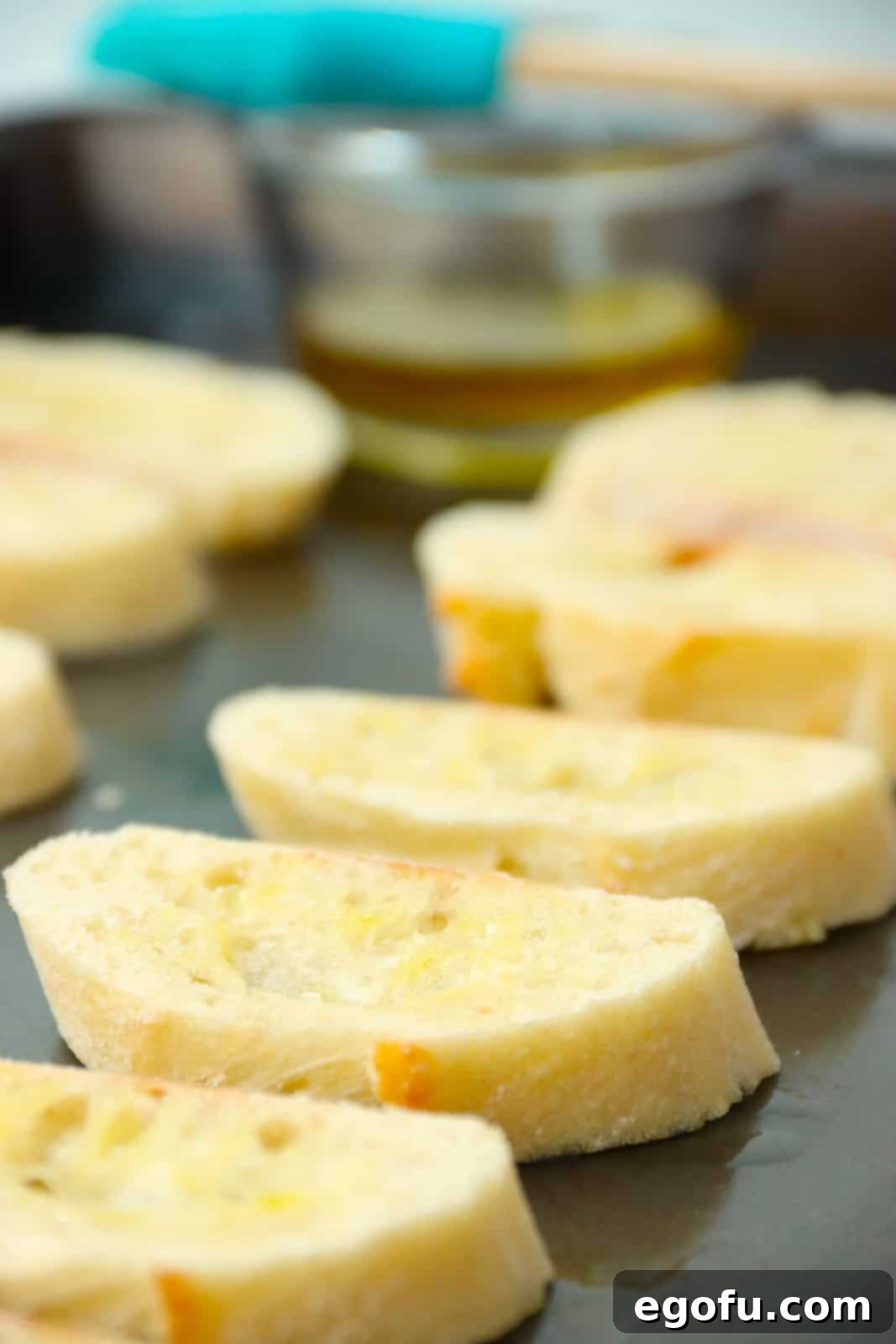 Garlic Parmesan Crostini 6 Sliced baguettes on baking sheet being toasted.