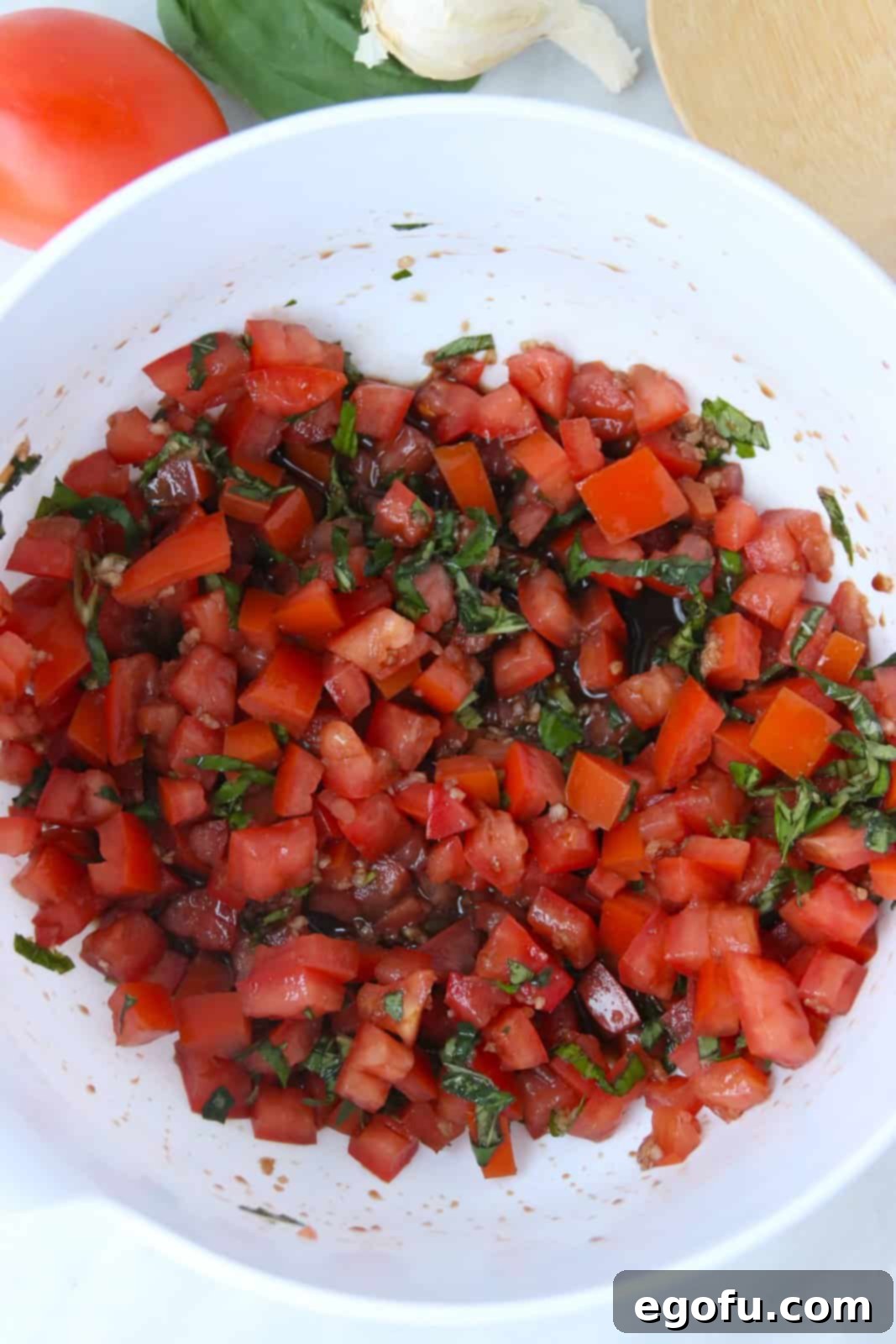 Garlic Parmesan Crostini 7 Bruschetta ingredients tossed together in bowl.