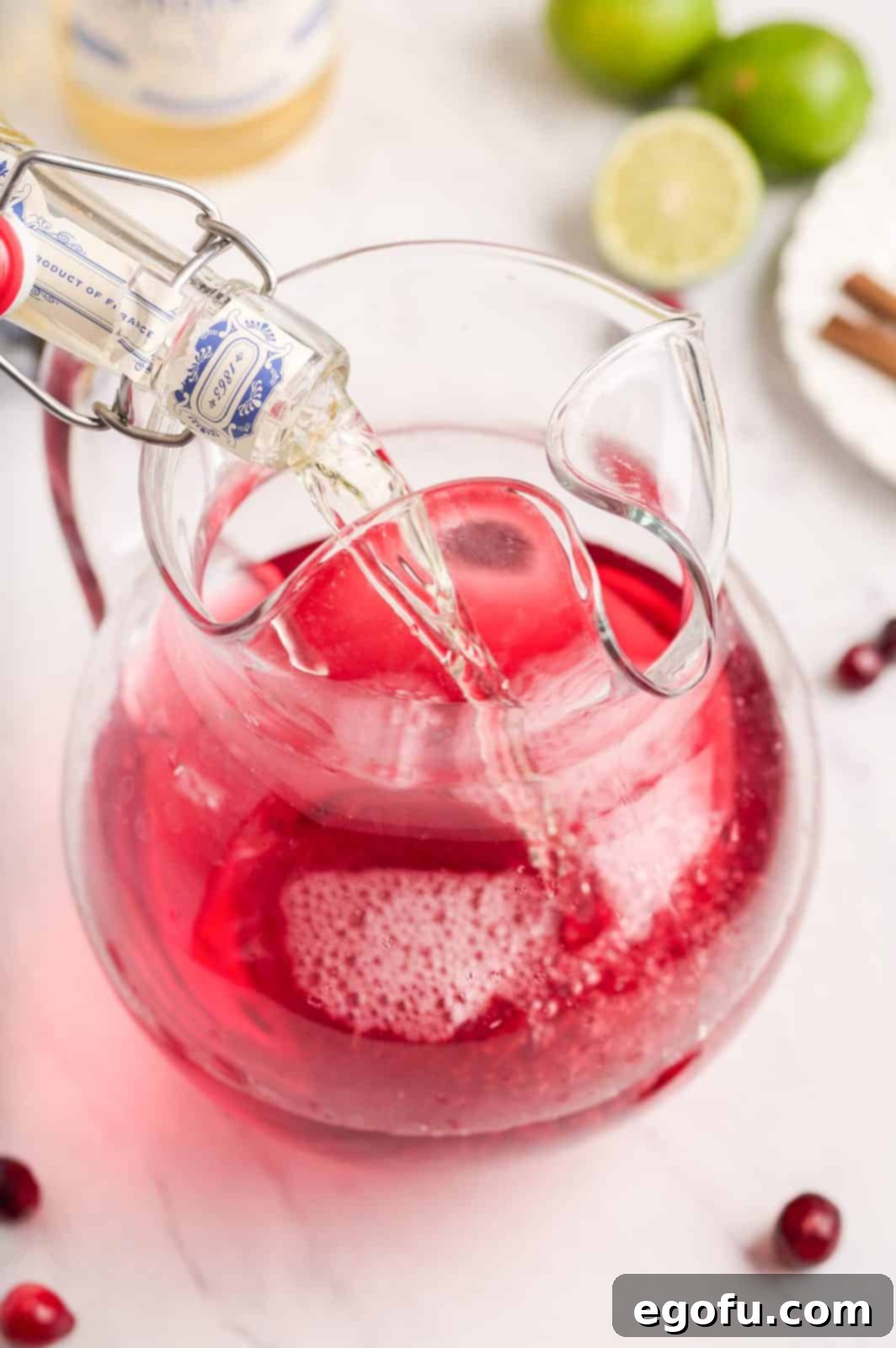 Crimson Bubbly 5 Wine and soda being added to pitcher. A key step in preparing the Cranberry Wine Spritzer.