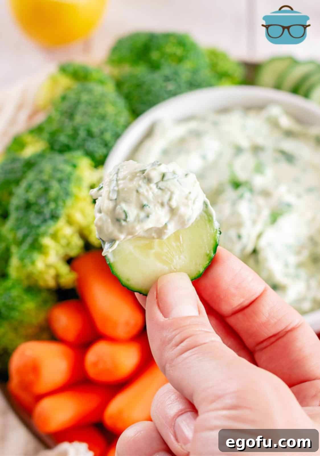 Chilled Garden Spinach Dip 7 A hand holding a fresh, vibrant green cucumber slice generously topped with a dollop of creamy spinach dip, showcasing a healthy and delicious option for dipping.