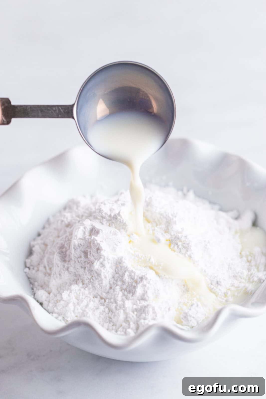Buttery Cherry Crumble Danishes 14 Glaze mixture being prepared in white dish.